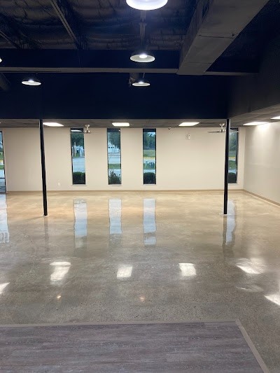 Spacious showroom with glossy concrete floors by Houston concrete polishing services, featuring modern lighting.