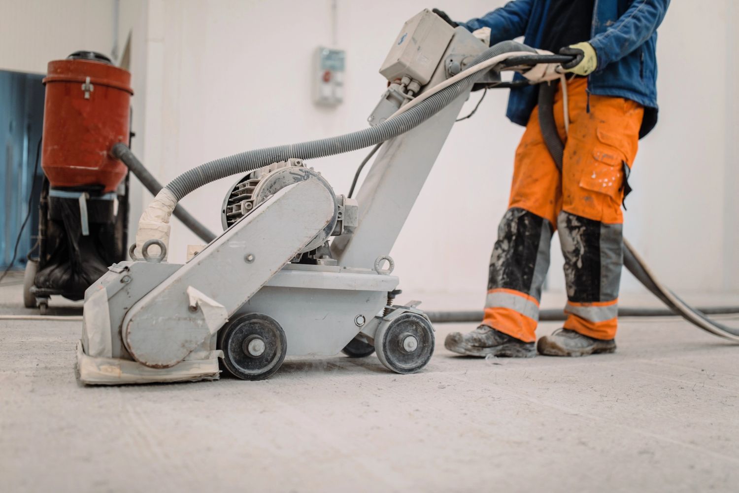 Polished cement contractors in Houston operating a grinder on a concrete floor for a smooth, professional finish.