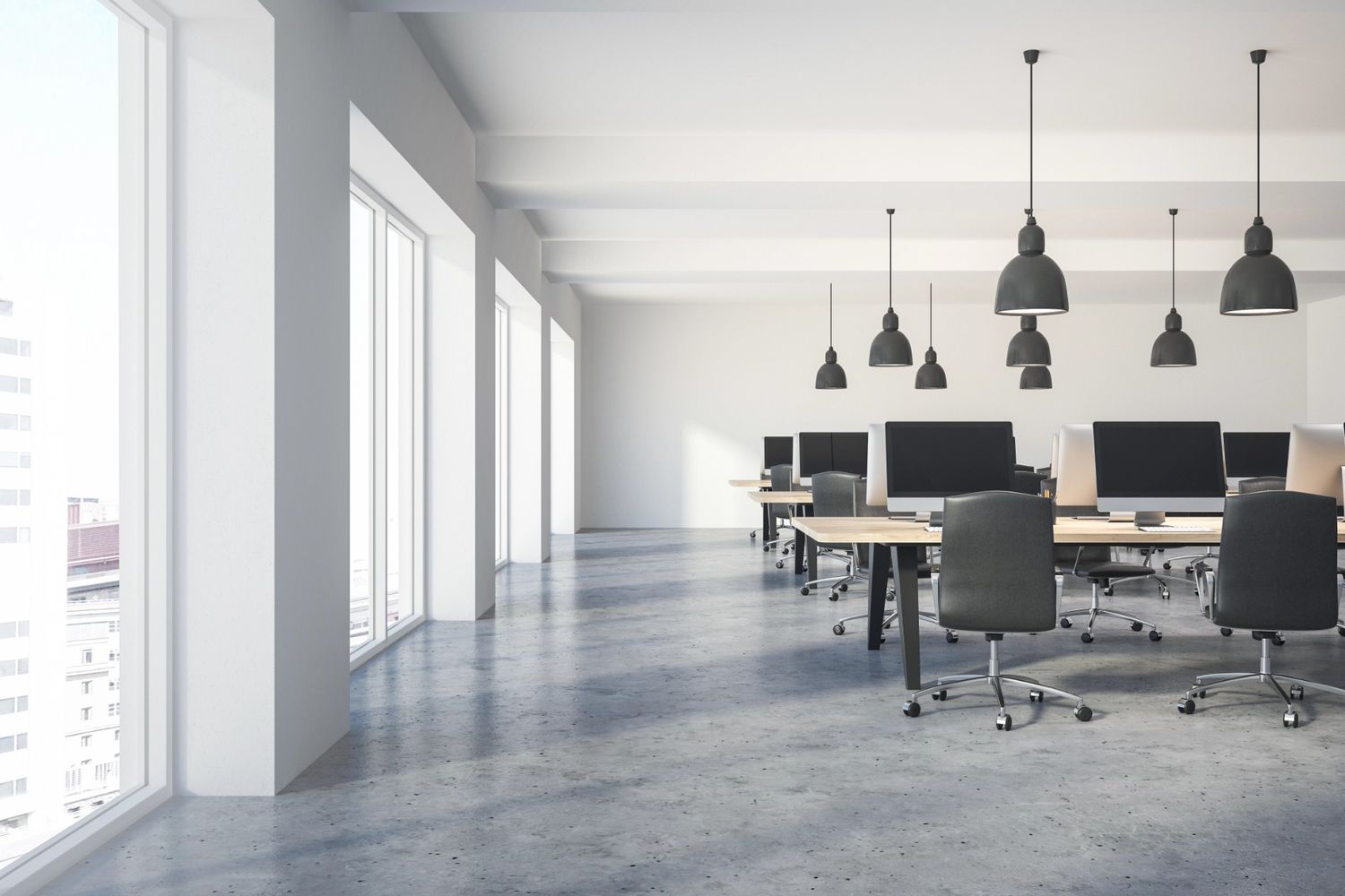 Modern office with polished concrete floors by Houston concrete polishing services, featuring desks and large windows.