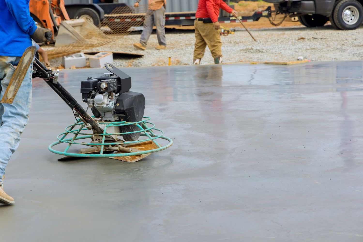 Worker using power trowel to smooth concrete surface for a polished finish by a cement company in Houston.