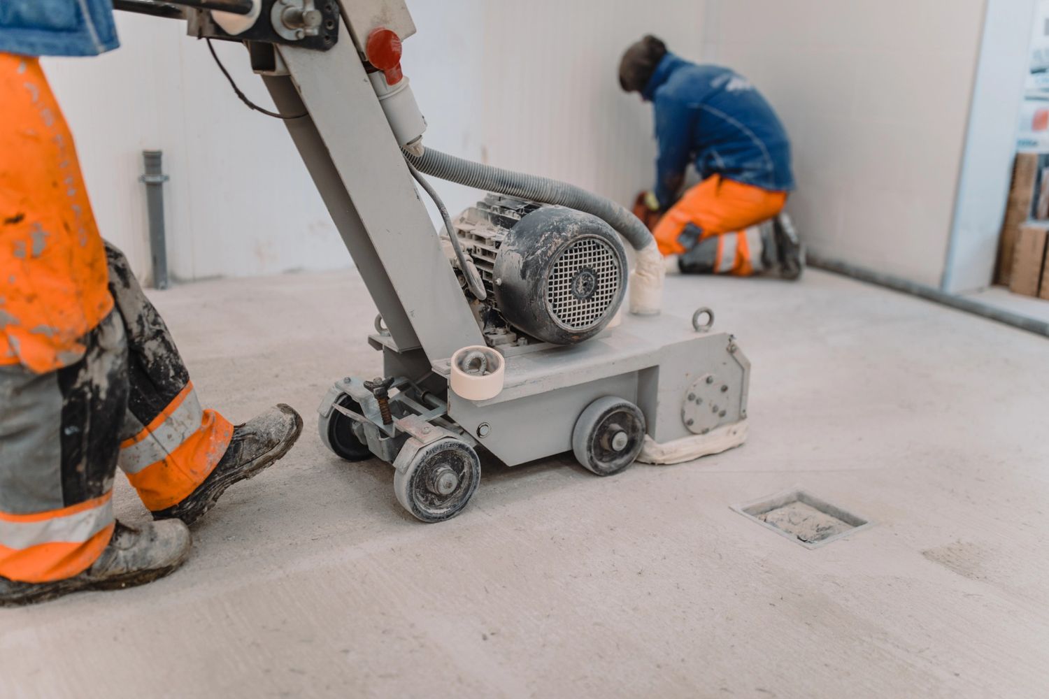 Polished cement contractors in Houston smoothing a concrete floor with a grinder for a glossy, durable finish.