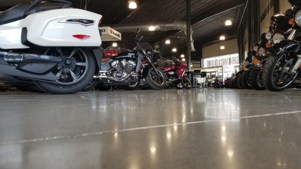 Motorcycle showroom with shiny polished cement floors, highlighting cement polishing company Houston expertise for durable finishes.
