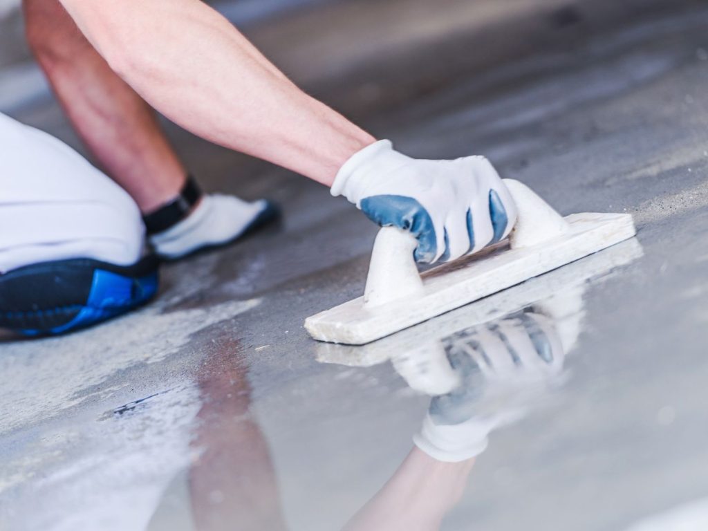 See an expert hand-finishing refinished cement flooring in Houston, ensuring a flawless and reflective surface for any space.