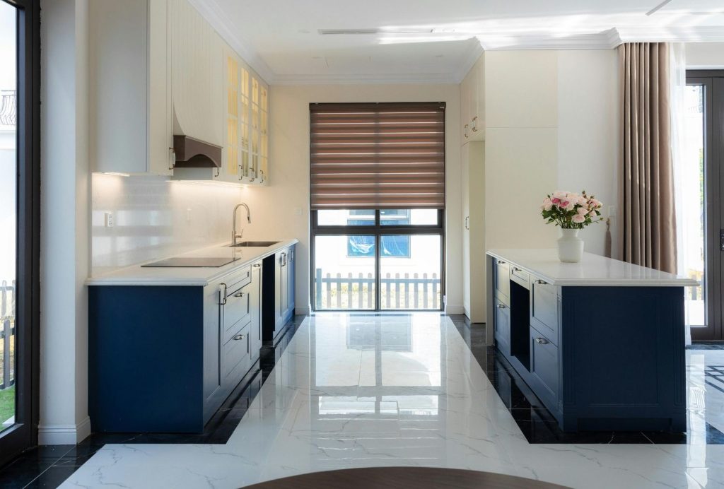 Modern white and navy kitchen featuring a bright, high-gloss marble-look refinished concrete flooring Houston finish.