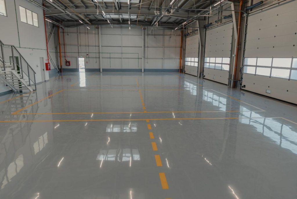 Industrial garage with smooth, durable gray refinished concrete flooring Houston and bright yellow safety markings.