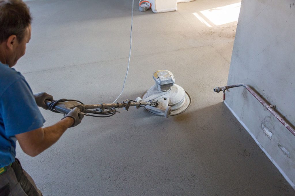 Worker using an edging grinder for precise, high-quality concrete finishing from a cement polishing company Houston.