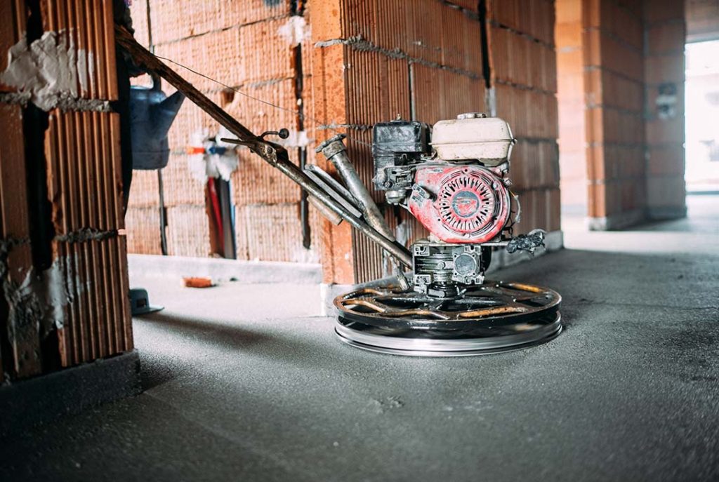 Contractor using a power float for commercial cement polishing flooring Houston installation service.