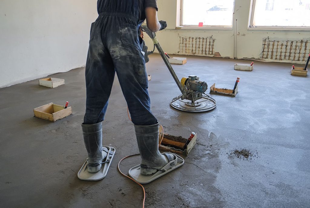 Worker finishing large floor slab for durable, seamless polished cement floors Houston commercial projects.
