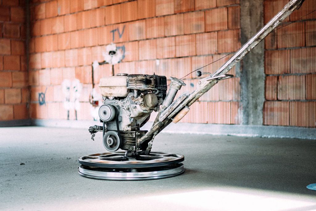 Heavy-duty power trowel smoothing cement, finished by polished concrete contractors Houston for quality.