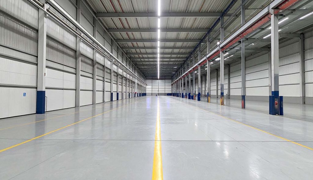 Spacious, high-gloss industrial warehouse floor demonstrating the strength of a cement polishing company houston finish.