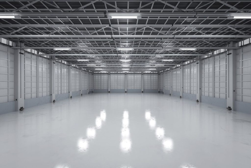 Extremely shiny white concrete floor in an empty industrial building. Work completed by cement polishing contractors Houston.