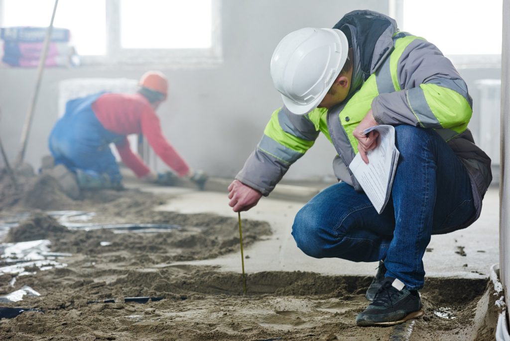 Polished concrete contractors Houston inspector measuring floor levels at a commercial construction job site.