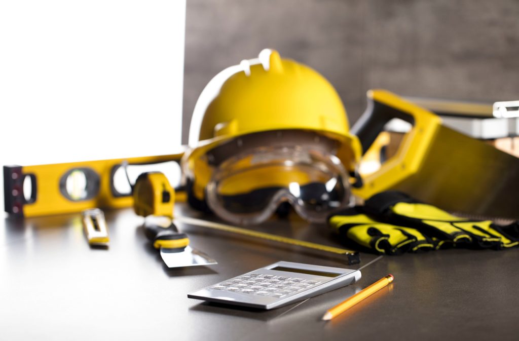 Safety gear and planning tools for polished concrete contractors Houston featuring a hard hat, goggles, and level.