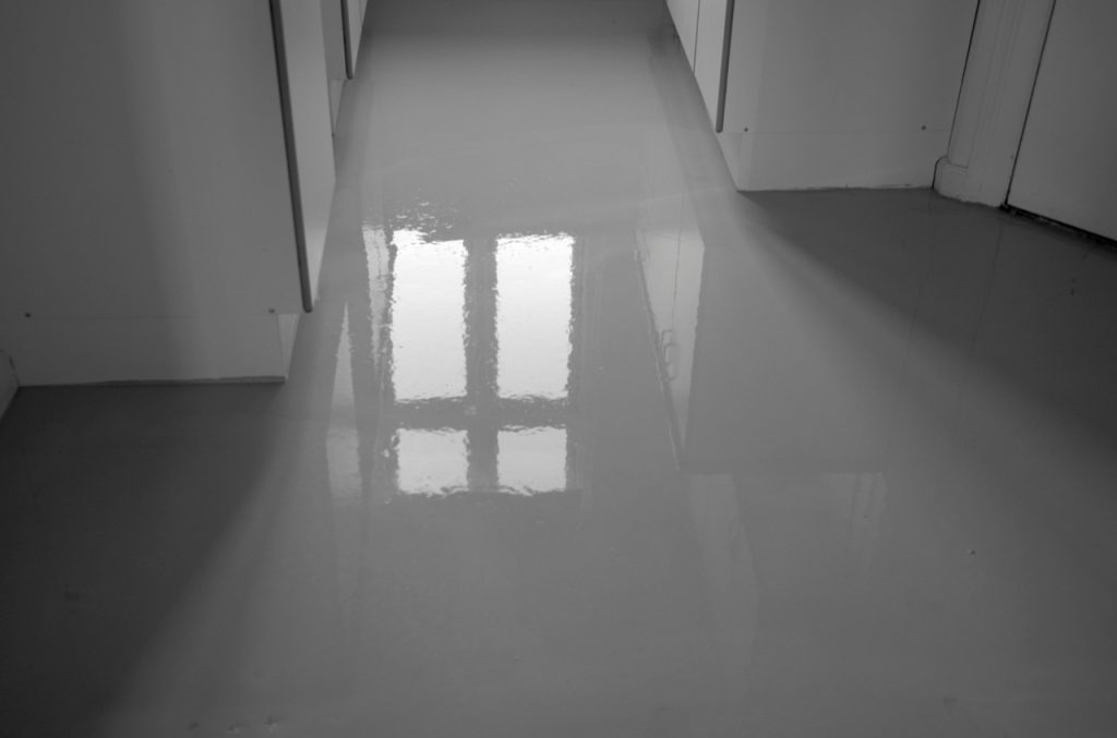 High gloss refinished cement flooring Houston residential hallway with a reflective finish and sleek modern design.