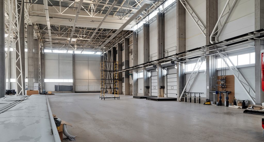 Industrial refinished cement flooring Houston facility with high ceilings, concrete pillars, and loading docks.