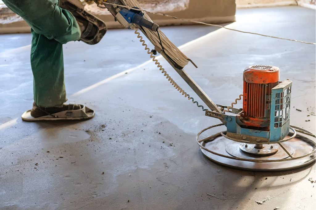 Industrial power trowel smoothing a surface for high-quality refinished concrete flooring Houston projects.