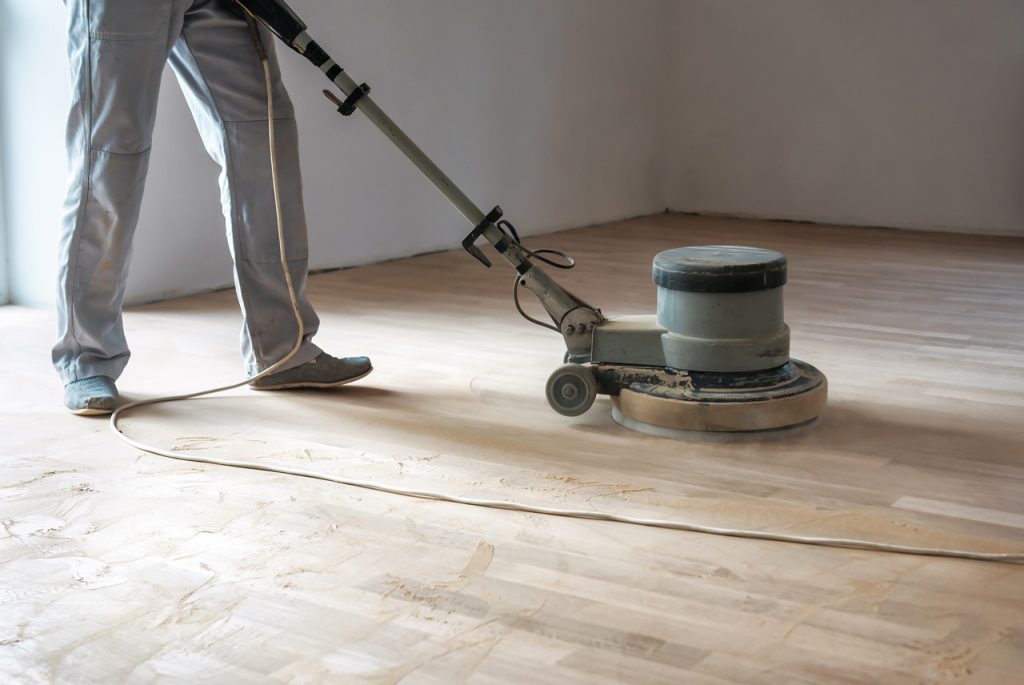 Professional polished concrete contractors Houston refinishing a residential wood-look floor with a floor buffer.