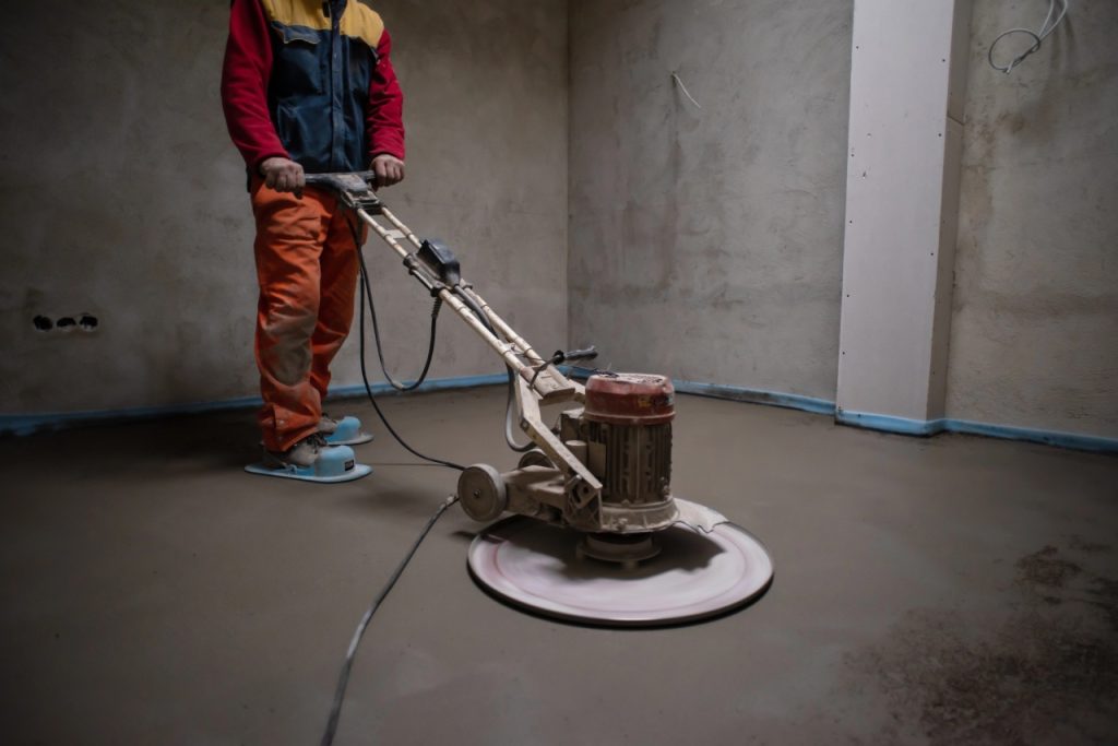Expert polished cement contractors Houston operating a rotary machine to create a sleek and durable floor finish.