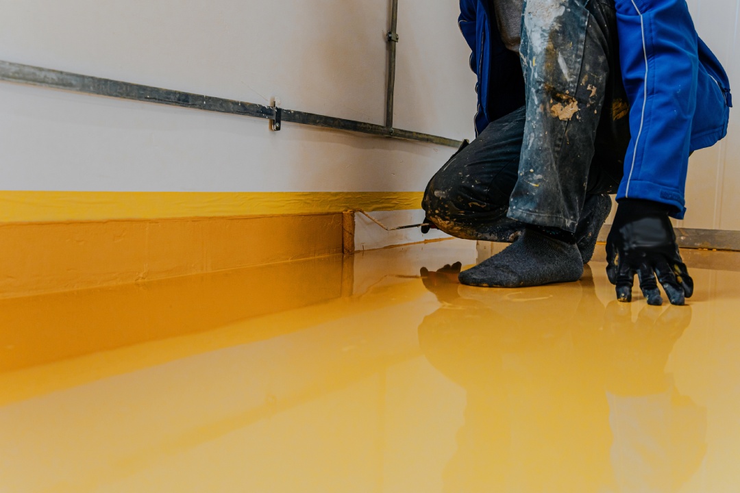 Skilled contractor performing concrete polishing floors Houston for a commercial space with a vibrant yellow finish.