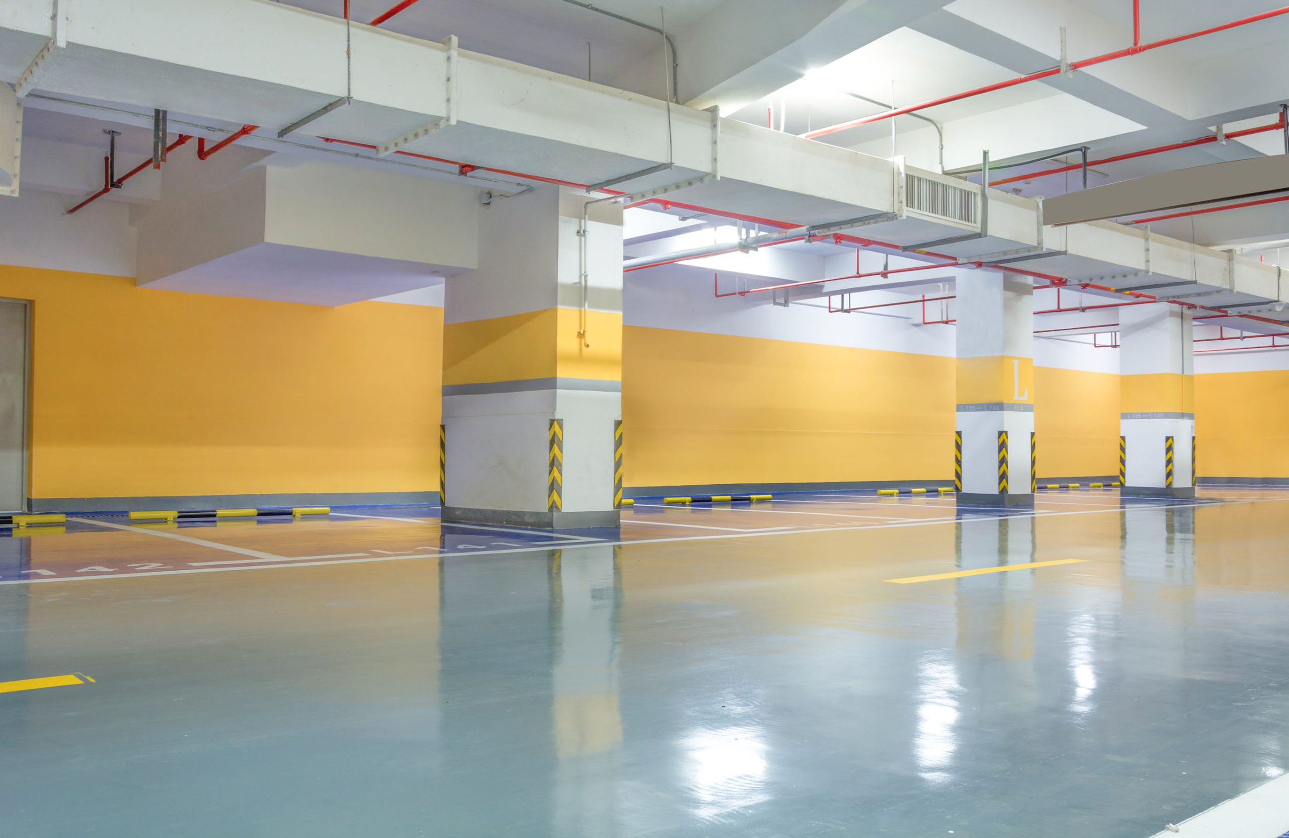 Brightly lit multi-level commercial parking garage with blue-toned polished concrete flooring Austin for durability.