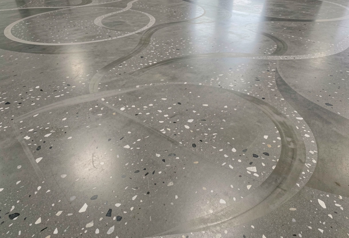 Elegant decorative terrazzo patterns integrated into polished concrete flooring Austin with white aggregate highlights.