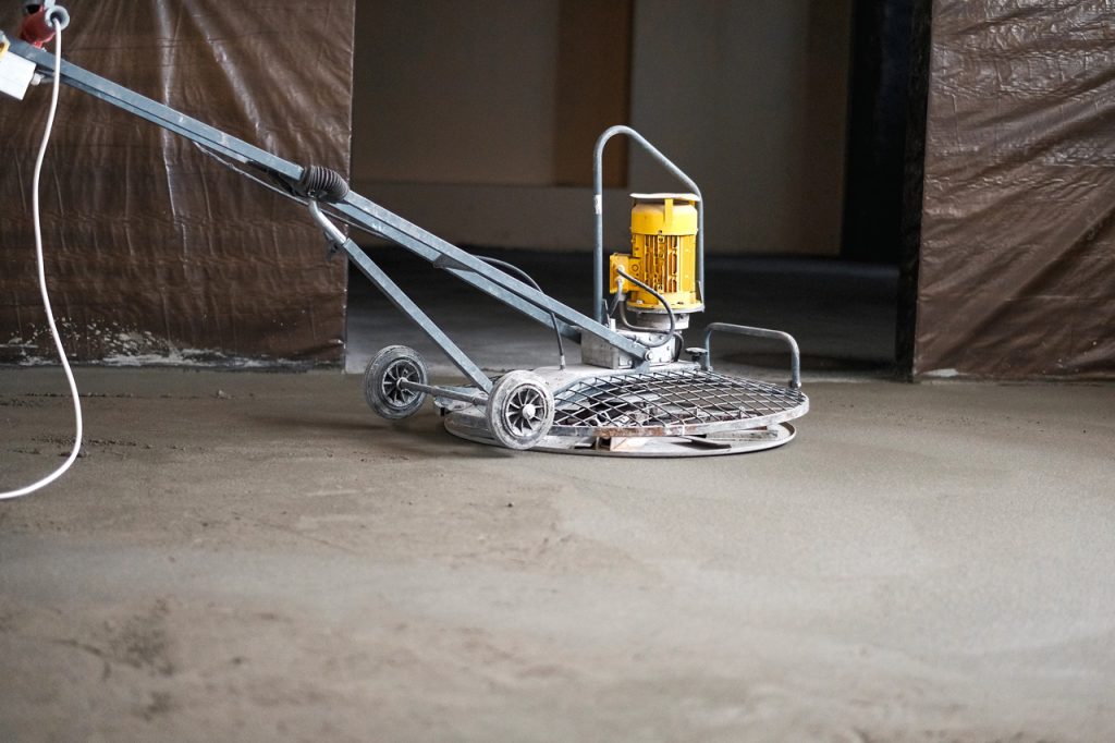 Professional electric polishing equipment smoothing a slab of refinished cement flooring Houston residential project.