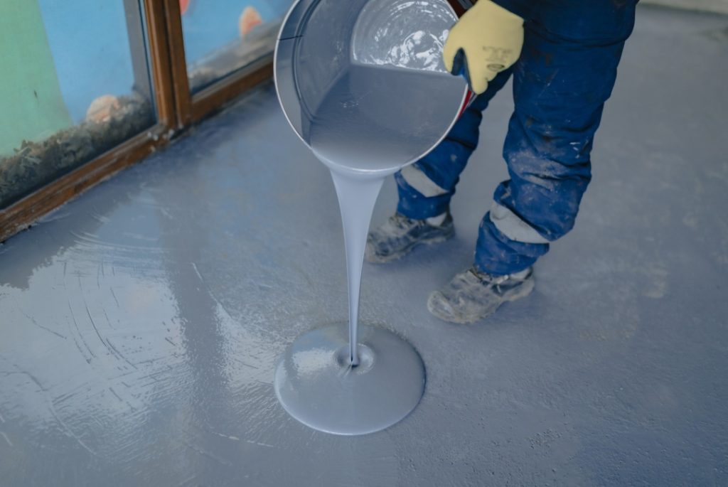 Professional pouring of grey epoxy for finished concrete flooring Houston commercial property renovation.