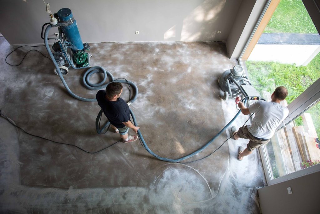 Contractors using industrial dust collection for high-quality refinished cement flooring Houston renovation project.