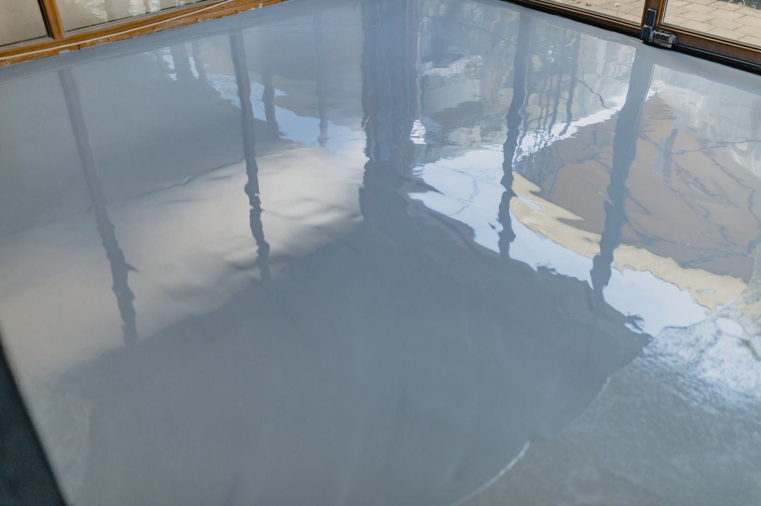 Close-up of a highly reflective liquid finish on premium polished concrete flooring Austin showing window reflections.