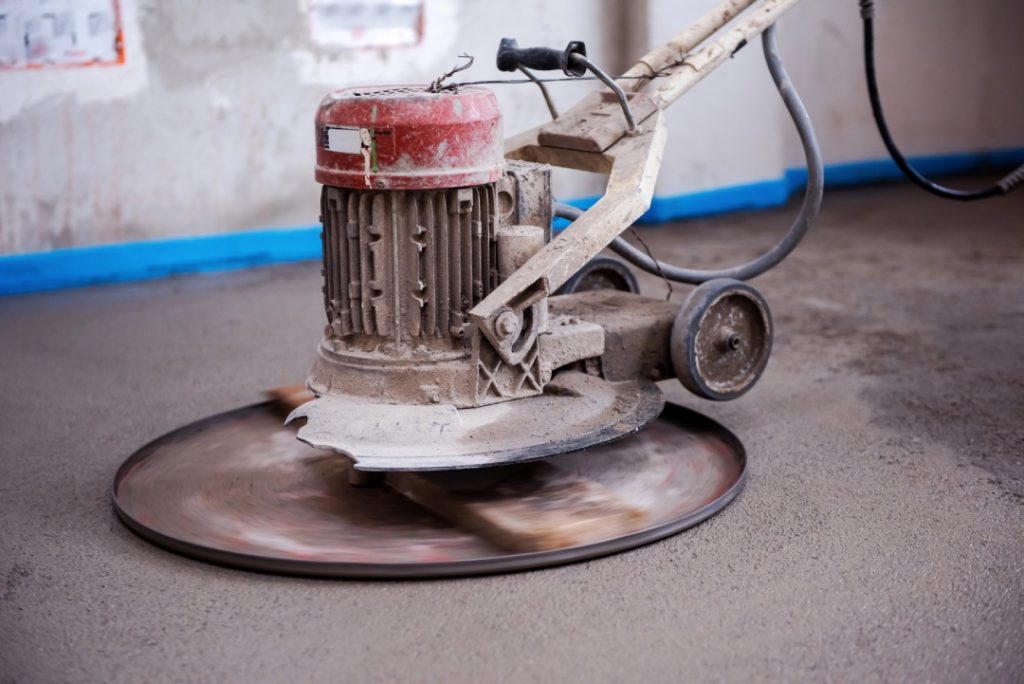 Close up of an electric polishing machine creating smooth finished cement flooring Houston on a new home site.