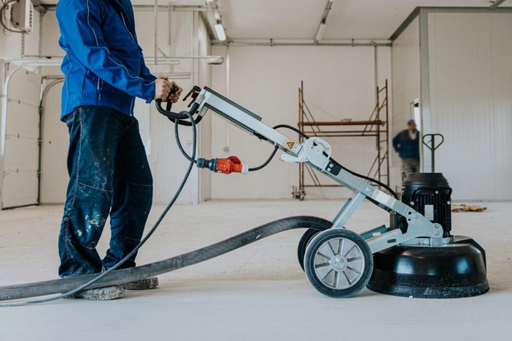 High-quality industrial polishing concrete services Houston specialist using a dustless floor grinder on a warehouse floor.
