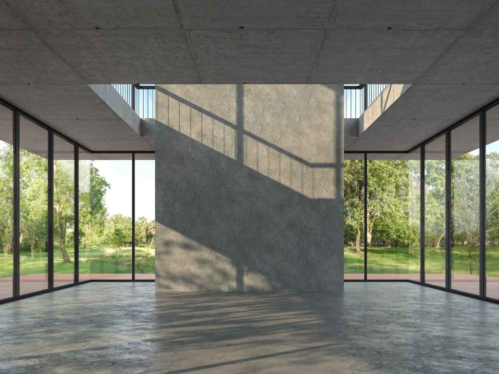 Luxury showroom with seamless polished cement floors Houston featuring floor-to-ceiling windows and lush greenery. 