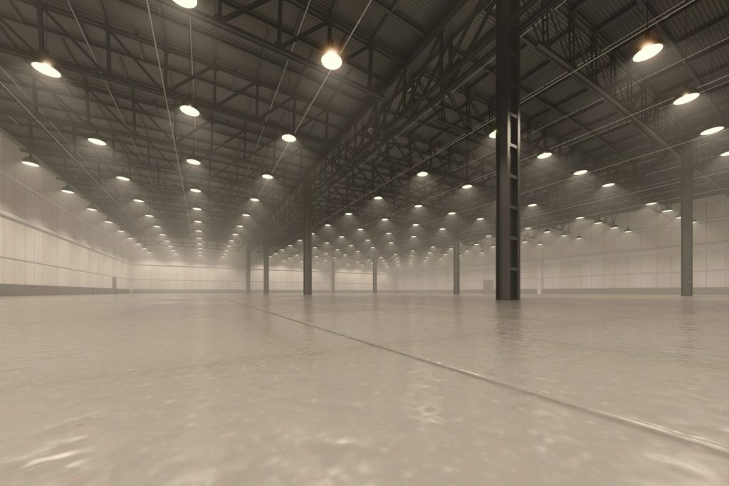 Spacious industrial warehouse featuring professional refinished concrete flooring Houston with warm overhead lighting.