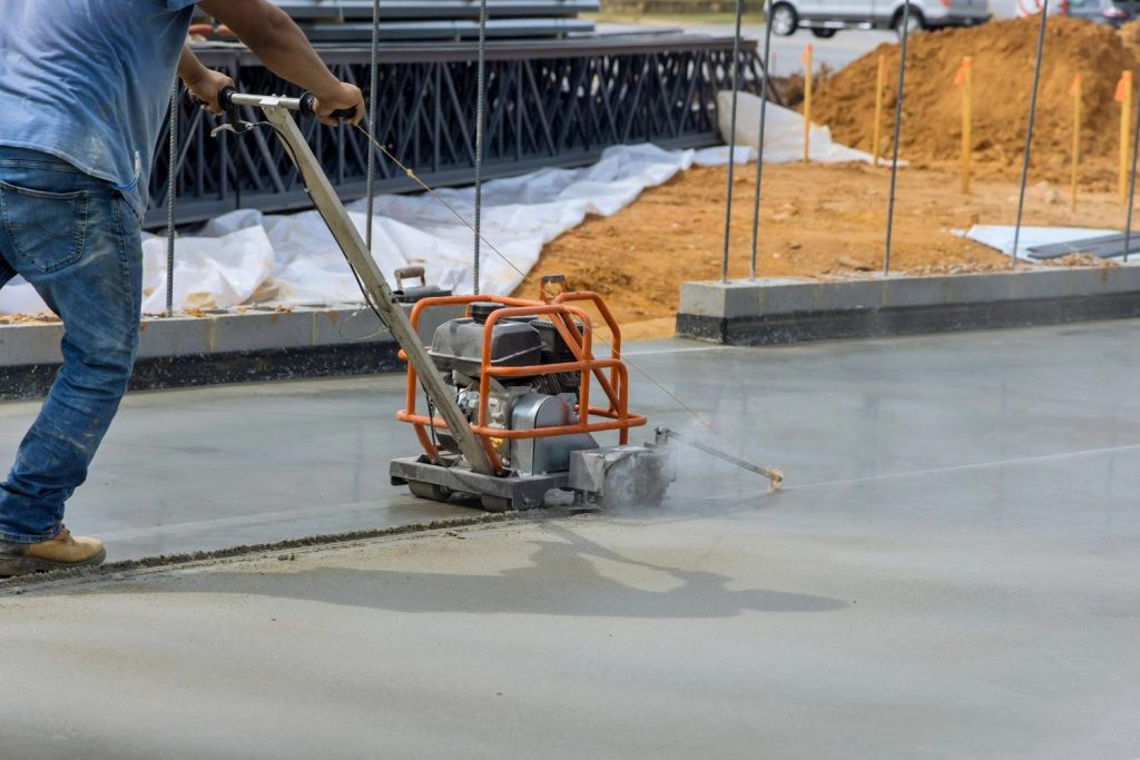 Contractor performing precision saw cutting on a new slab to create durable shiny cement flooring Houston projects.