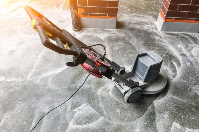 Professional cement polishing contractors in Houston operating a floor grinder on concrete surface for a smooth finish.
