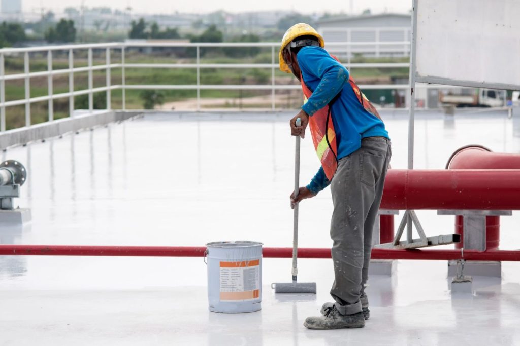 Worker applying coating on rooftop surface for a polished finish by a cement company in Houston.