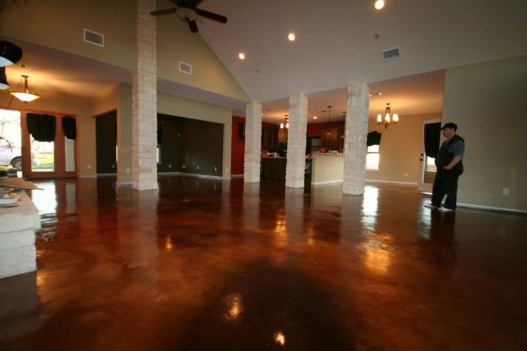 Expert concrete polishing contractors Houston transforming a spacious living room with rich brown stained and polished concrete flooring for durable elegance.