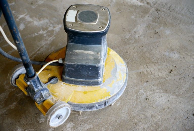 Cement polishing contractors Houston use industrial machine to smooth concrete surface. Yellow base and swirl marks shown.