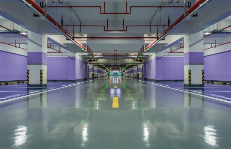 Spacious underground parking garage with polished cement floors and purple walls, expertly finished by a leading cement polishing company in Houston for durable, high-shine surfaces.