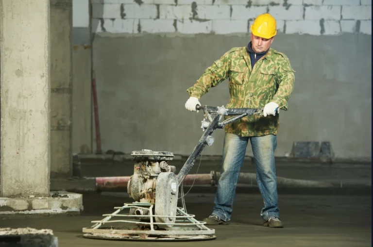 Professional worker using power trowels for cement polishing flooring in Houston construction site.