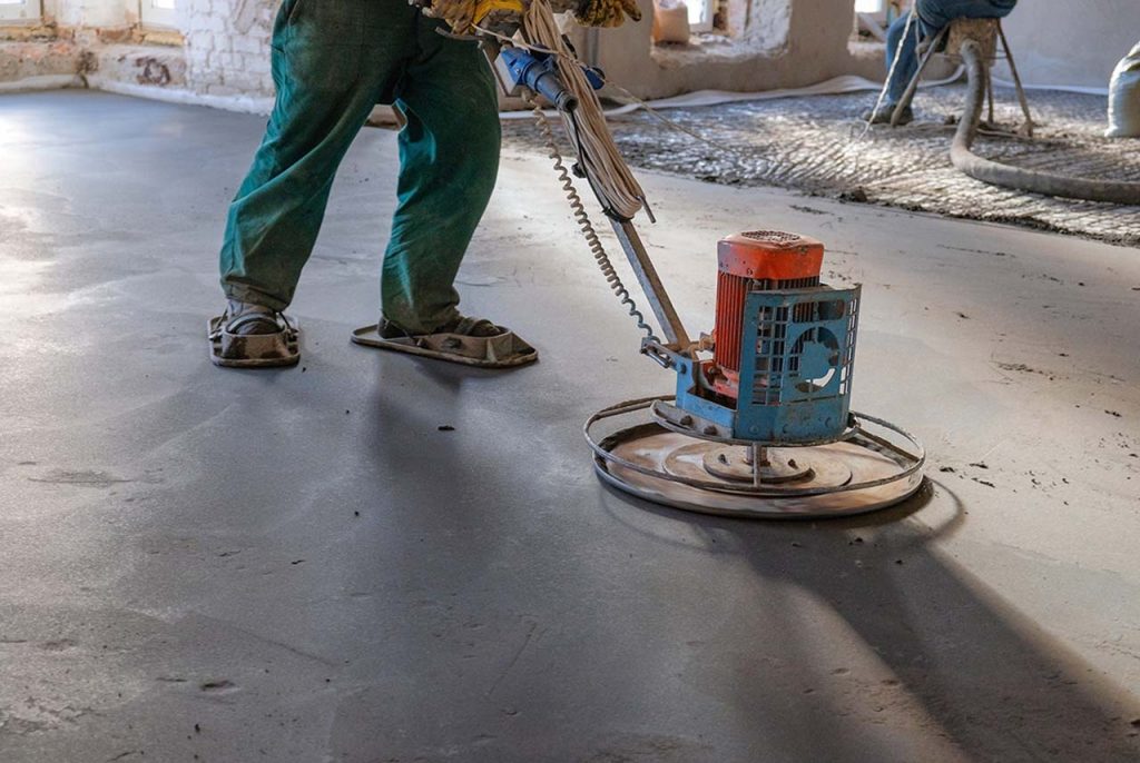 Professional contractor using a power trowel for high-quality refinished concrete flooring Houston residential projects.
