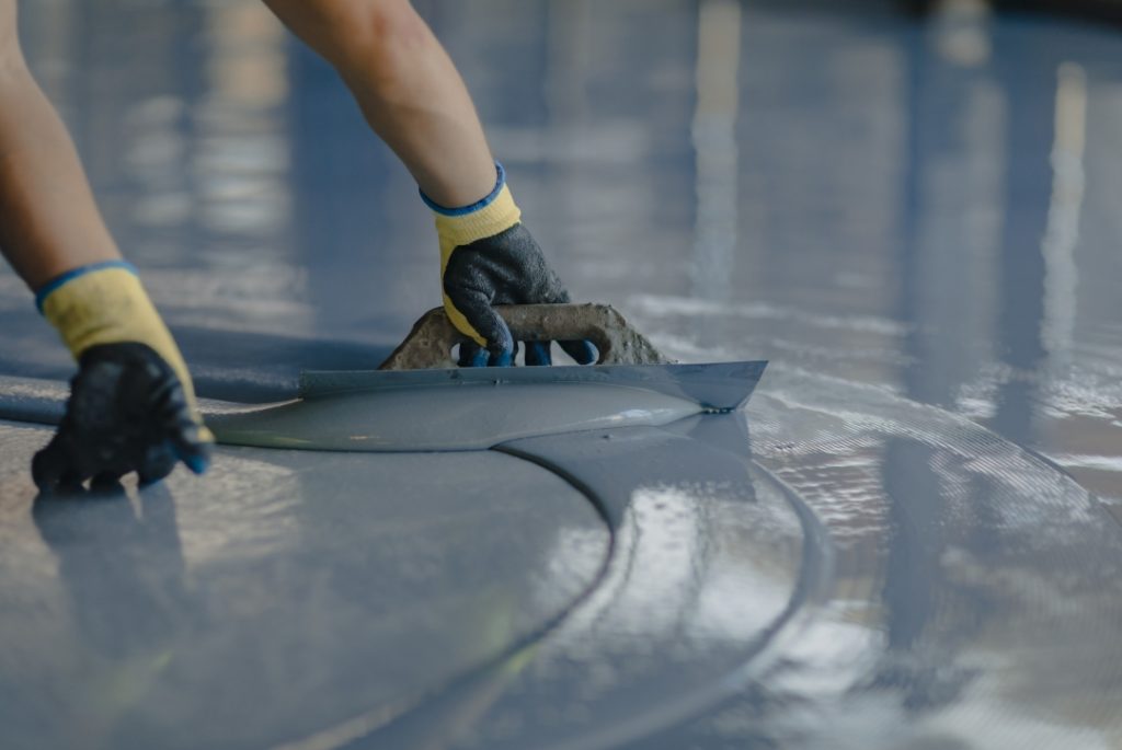 Expert smoothing of a self-leveling overlay for finished concrete flooring Houston industrial workspaces.