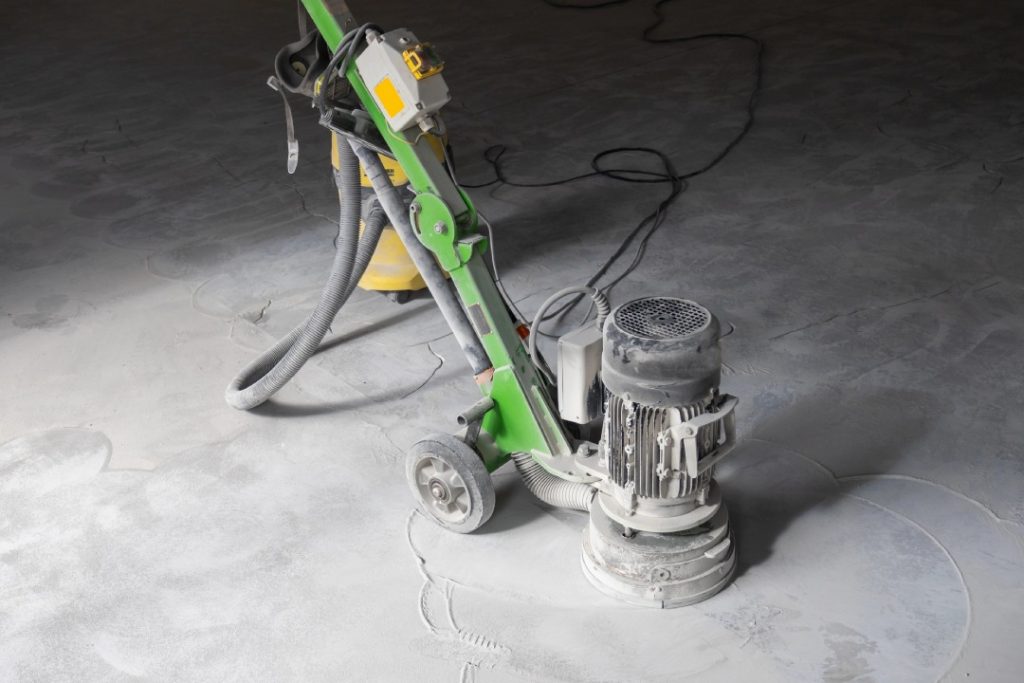 Industrial floor preparation using a heavy-duty grinder by a professional polished concrete company Houston experts.