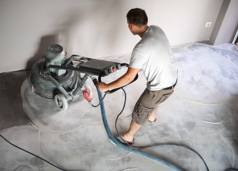 Specialist using a heavy duty floor grinder for smooth and polished refinished cement flooring Houston home surfaces.