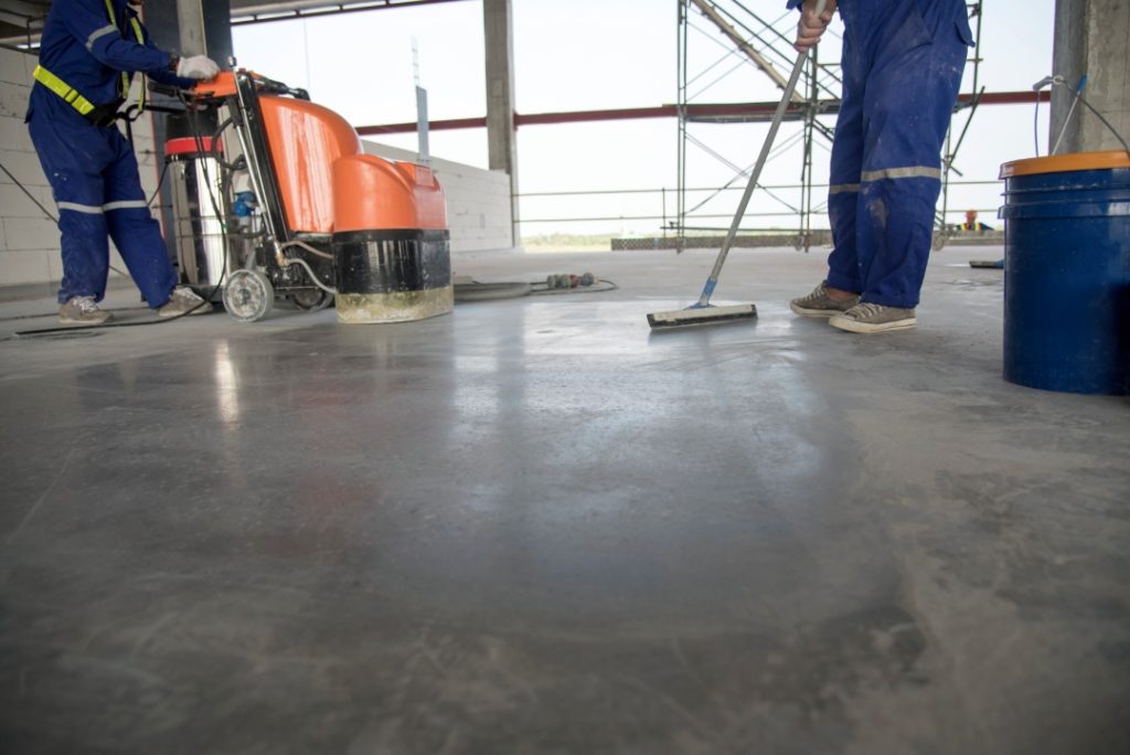 Expert polishing concrete services Houston technicians finishing a large commercial floor in a new building project.