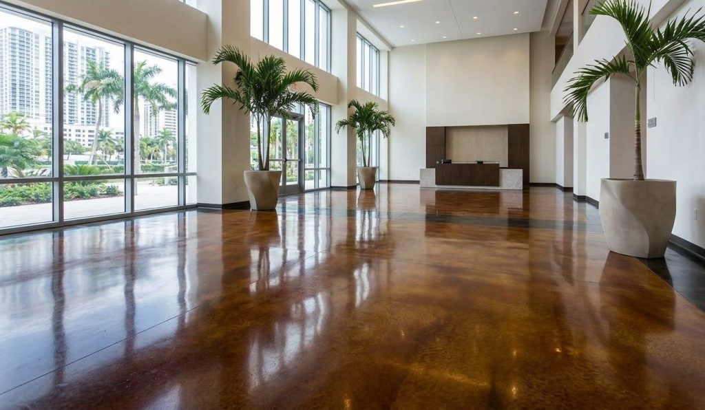 A high-gloss of amber and charcoal refinished concrete flooring in a modern lobby in Houston, reflecting natural light.