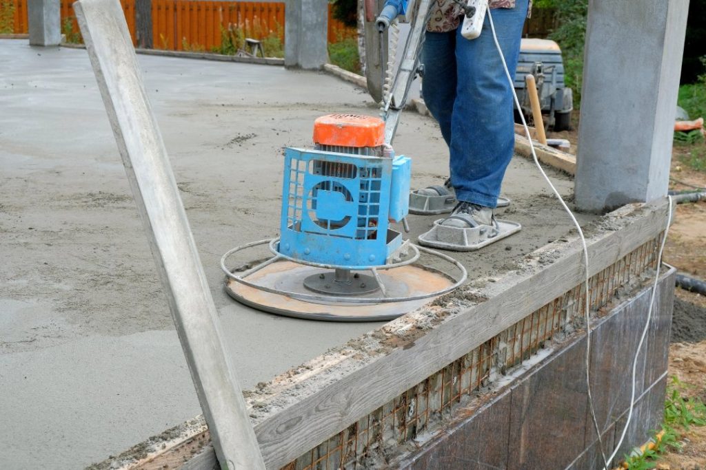 Professional uses electric power trowel to achieve a shiny cement flooring Houston finish on a new home patio.