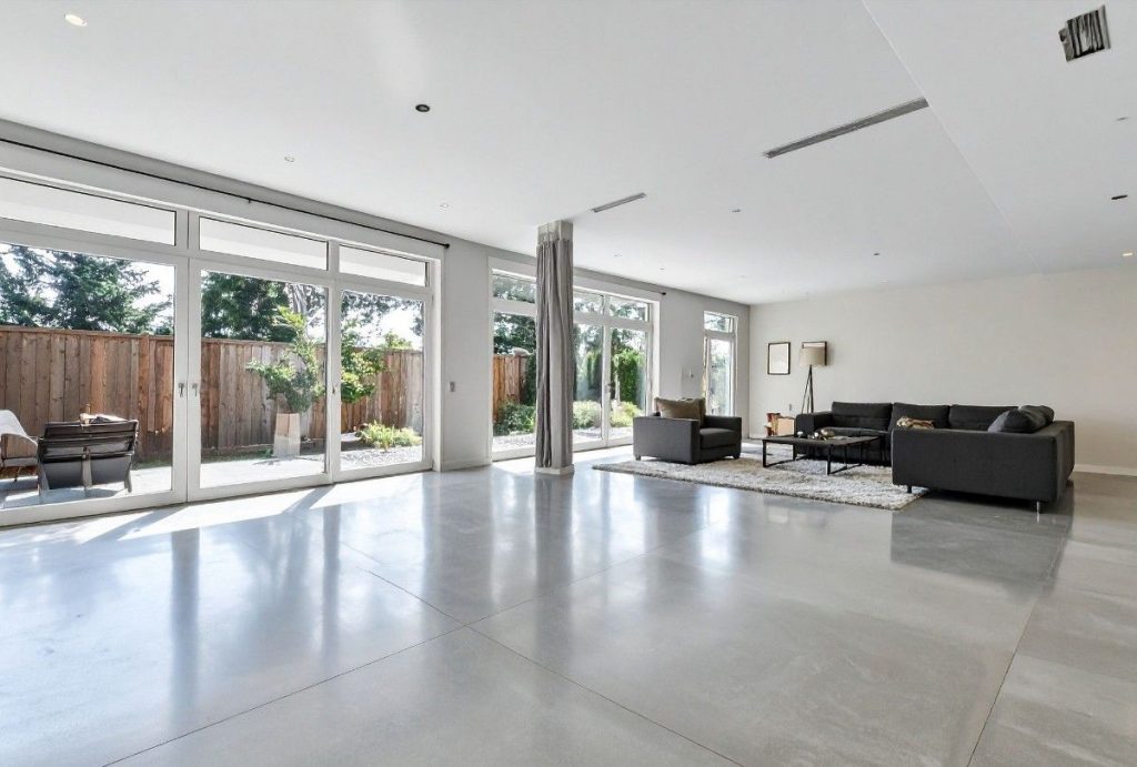 A seamless, highly-reflective polished concrete floor in a luxury living room, expertly installed by polished concrete contractors houston.