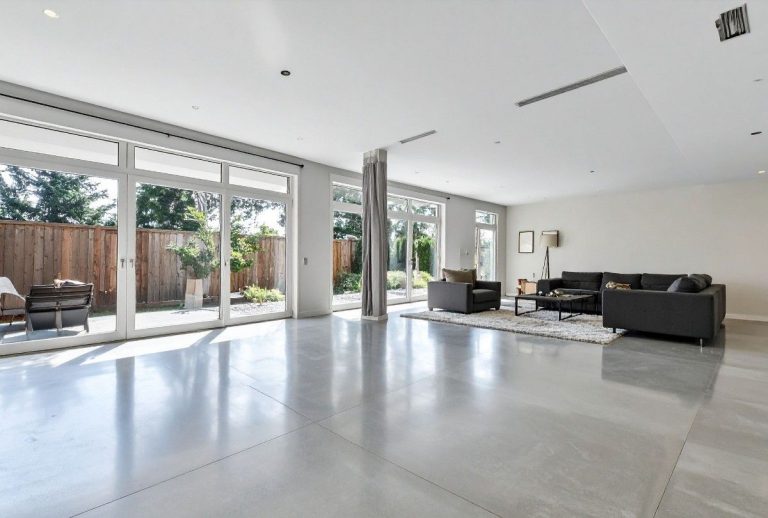 A seamless, highly-reflective polished concrete floor in a luxury living room, expertly installed by polished concrete contractors houston.