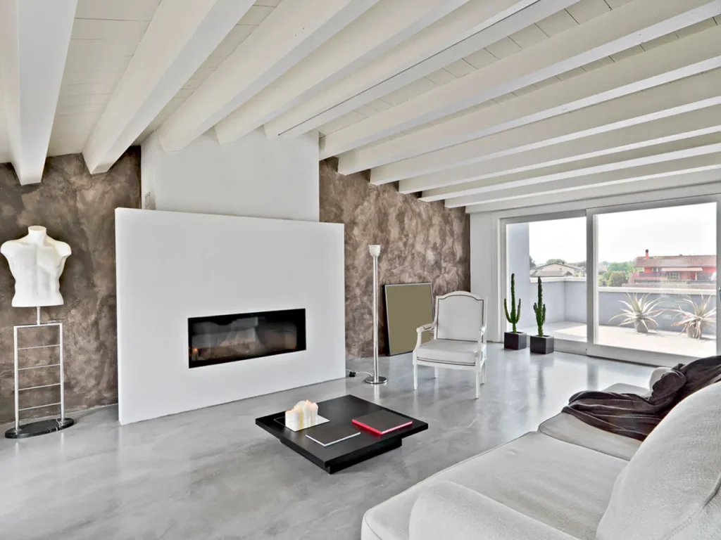 A sleek grey floor installed by a top Polished cement company houston anchors this modern living room with beamed ceilings.